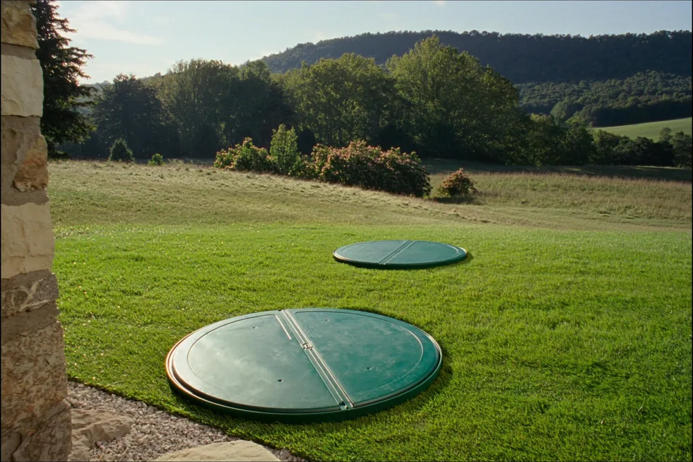 Septic tank access risers set flush in a lawn beside a home in Sevier County, Tennessee